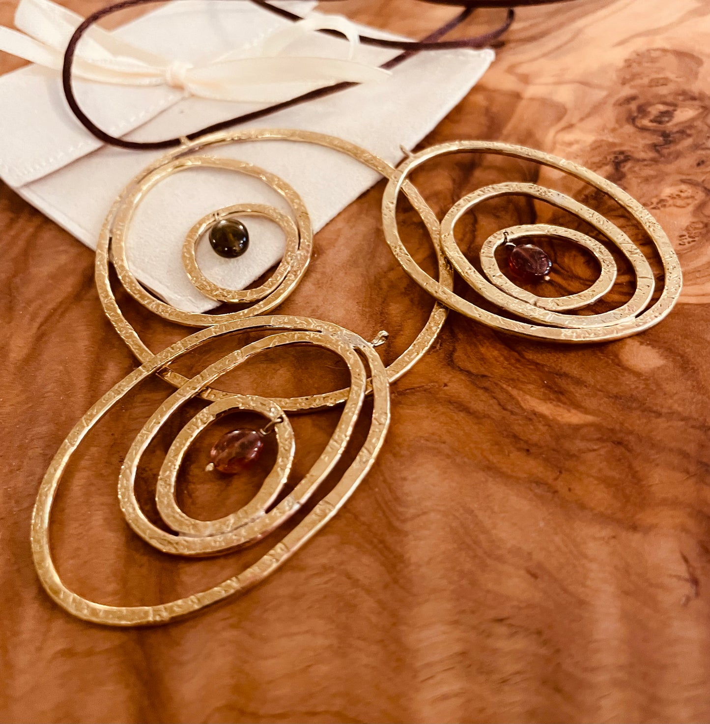 "Silenzi in orbita... Nelle orbite vuote, stelle di silenzio, tracce di un passato che sfugge e ritorna."  -   Linea 'Orbite': ciondolo, orecchini e anello in ottone martellato con tormalina.