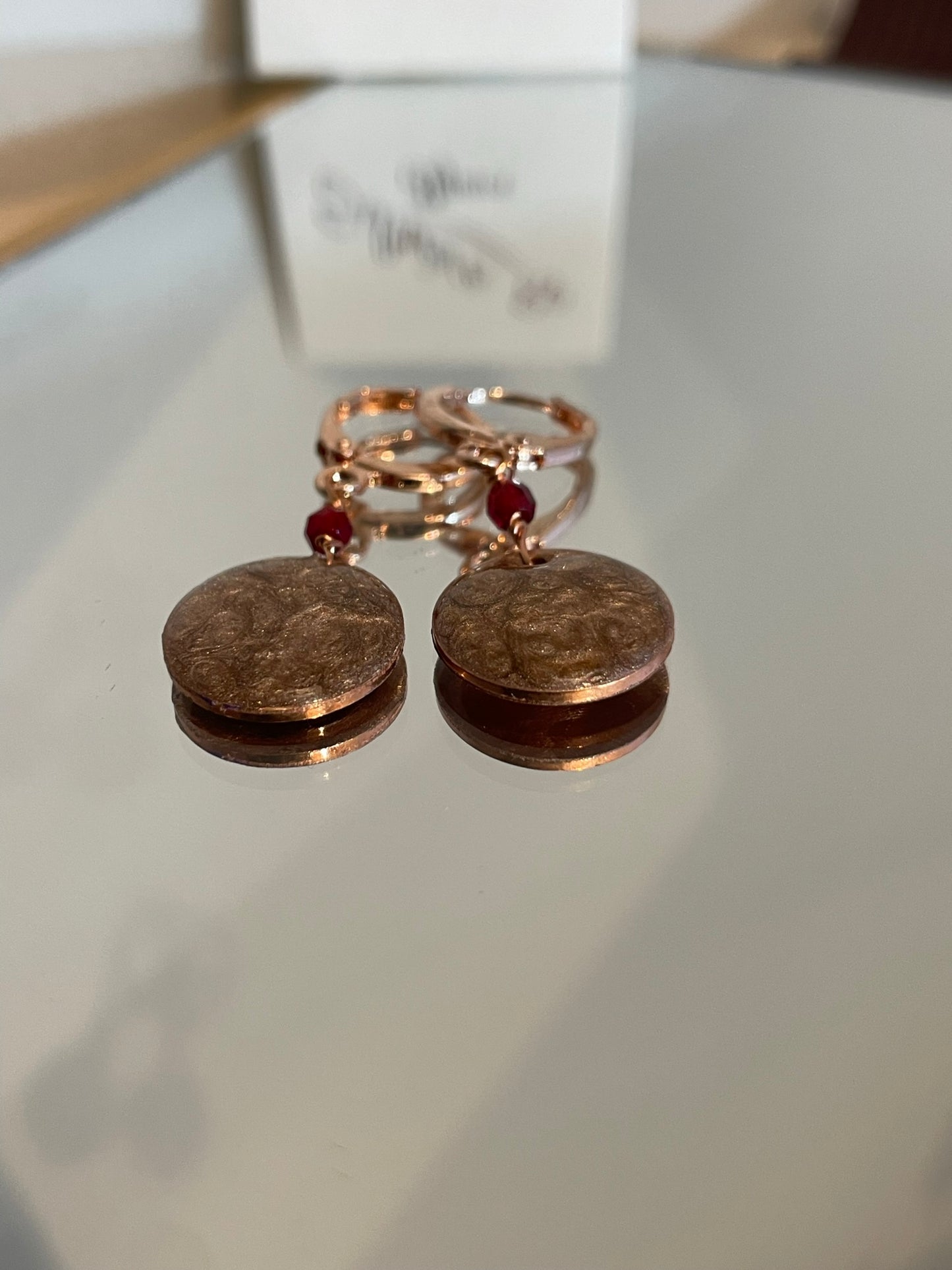 Copper pendant earrings embellished with small crystals.