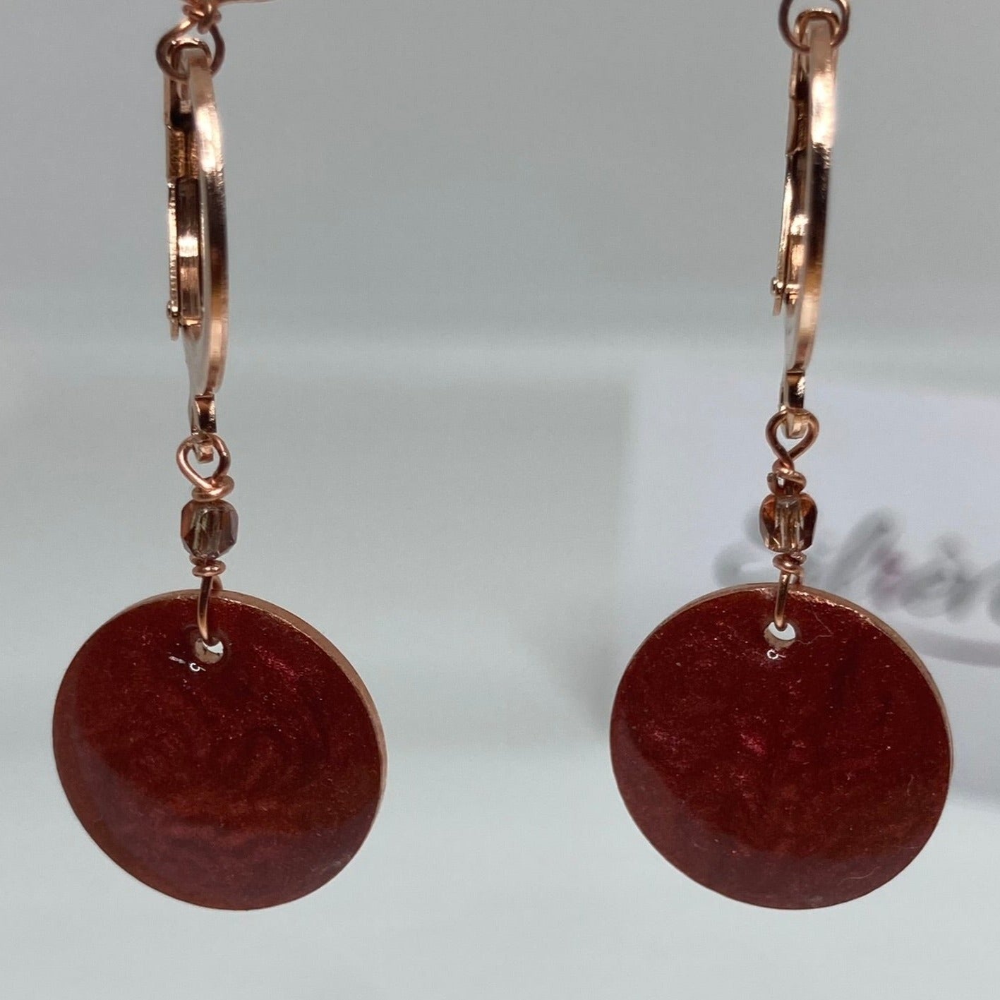 Copper pendant earrings embellished with small crystals.