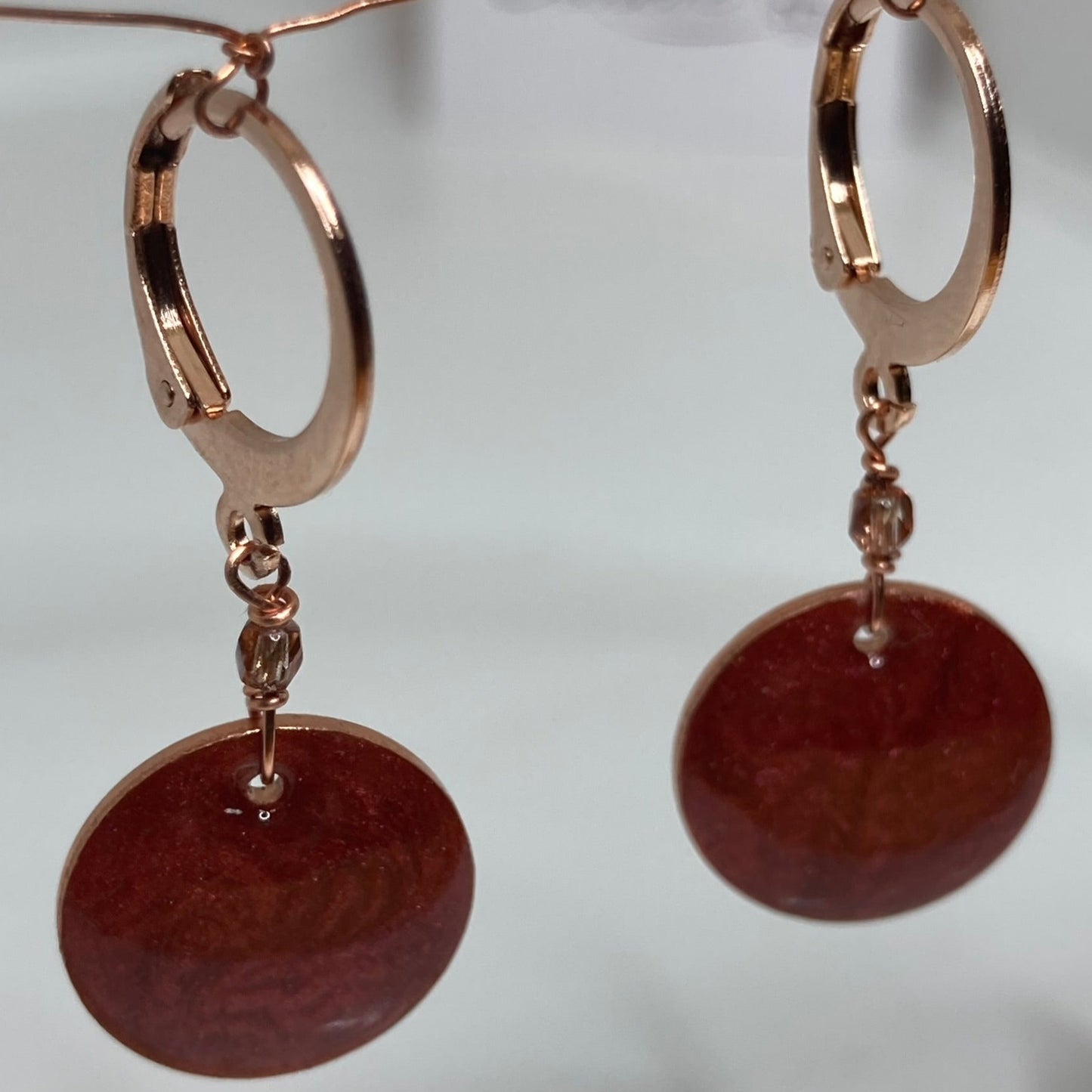 Copper pendant earrings embellished with small crystals.