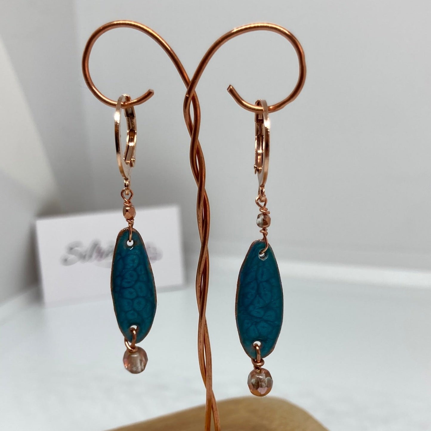 Copper pendant earrings embellished with small crystals.