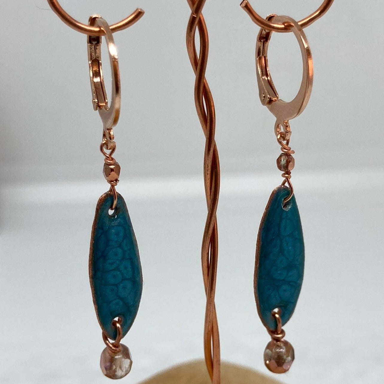 Copper pendant earrings embellished with small crystals.