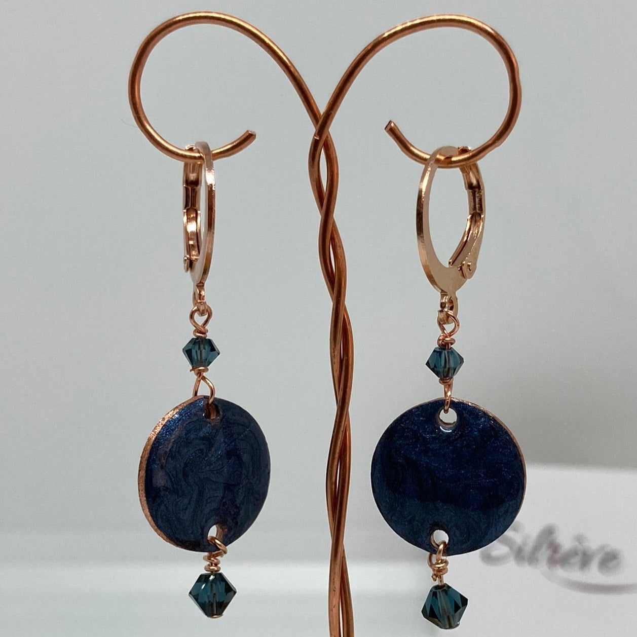 Copper pendant earrings embellished with small crystals.