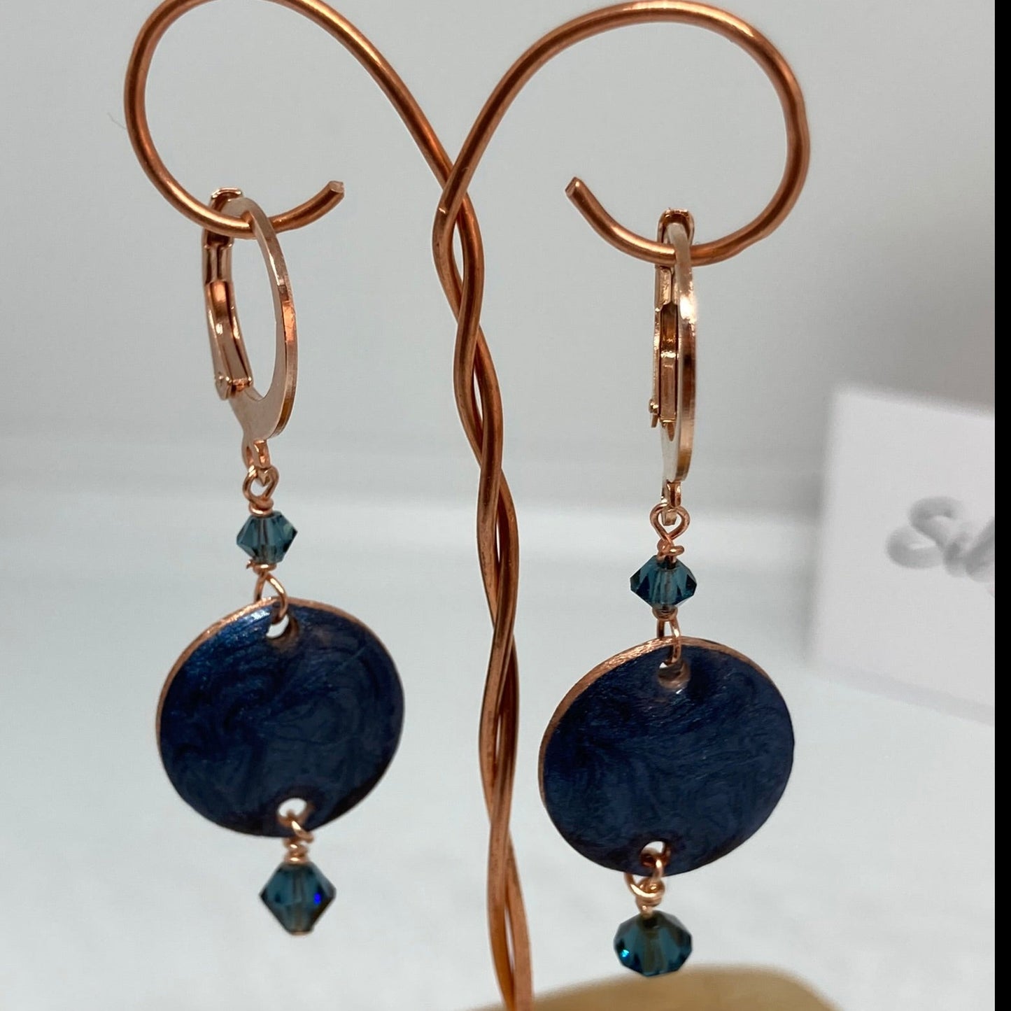 Copper pendant earrings embellished with small crystals.