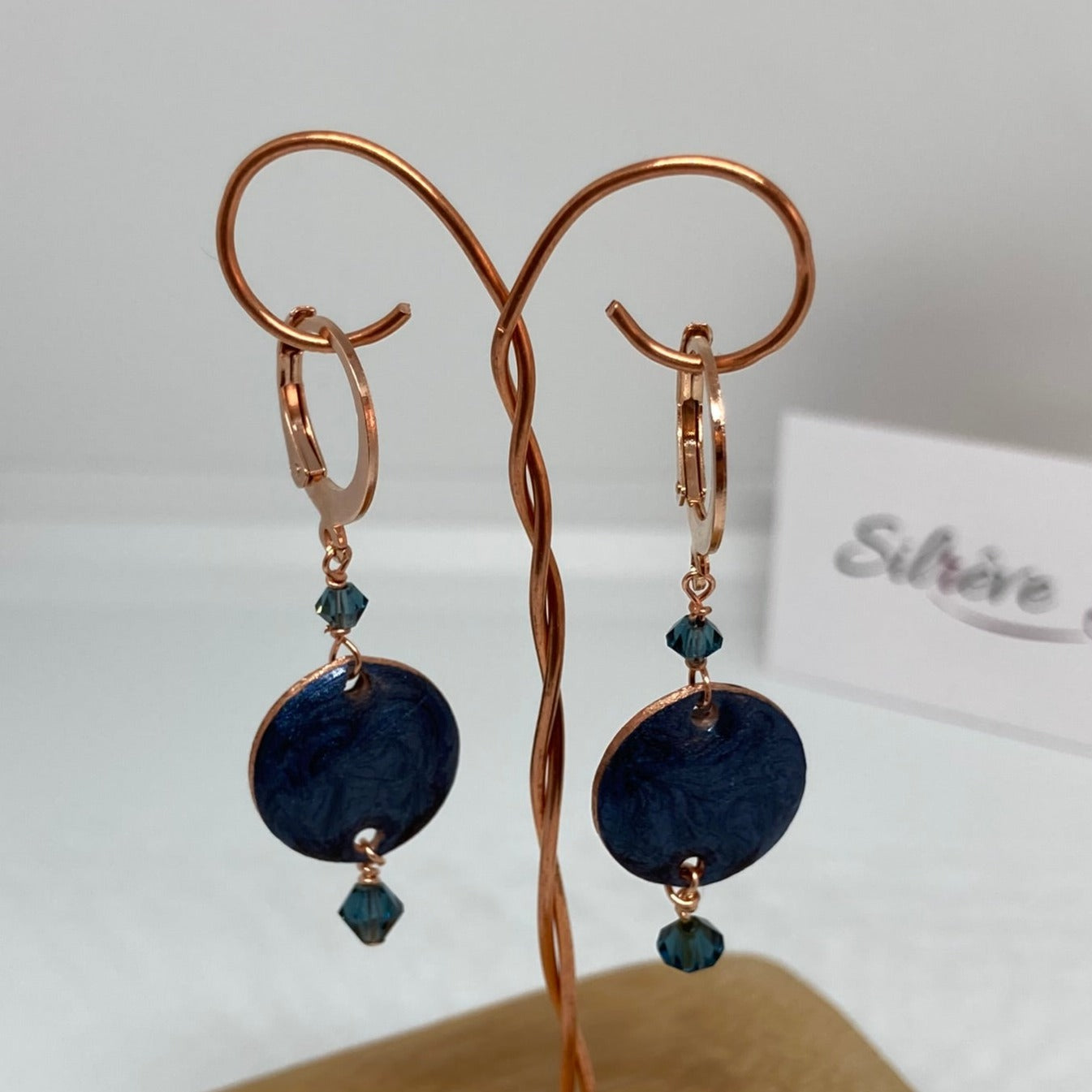 Copper pendant earrings embellished with small crystals.