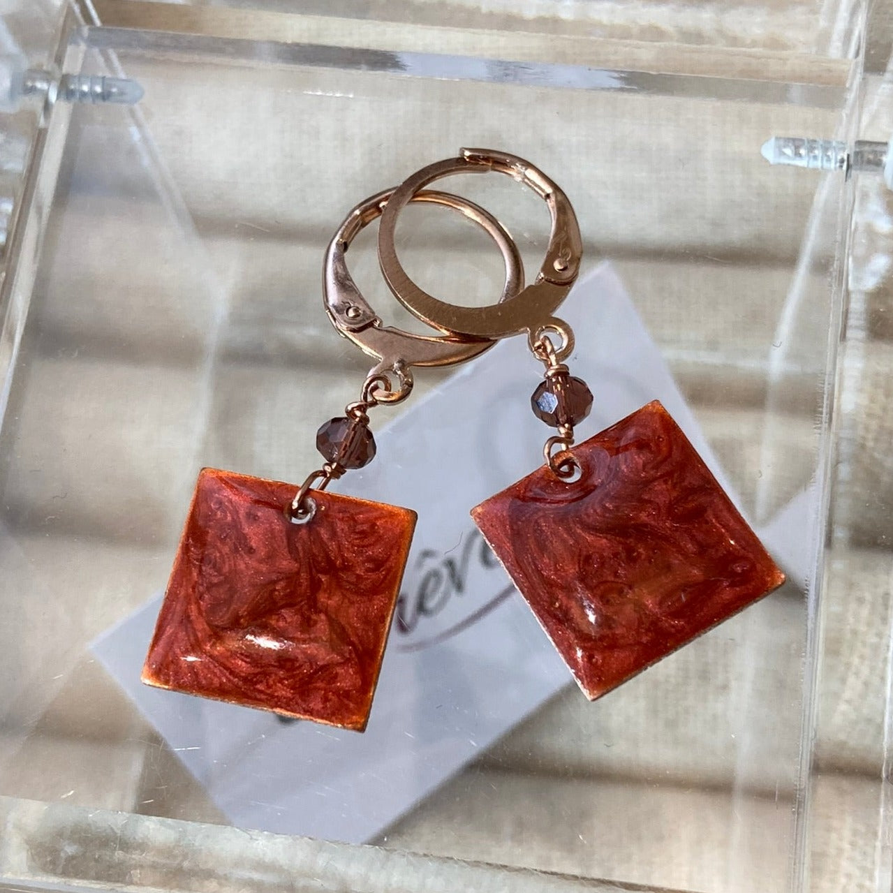 Copper pendant earrings embellished with small crystals.