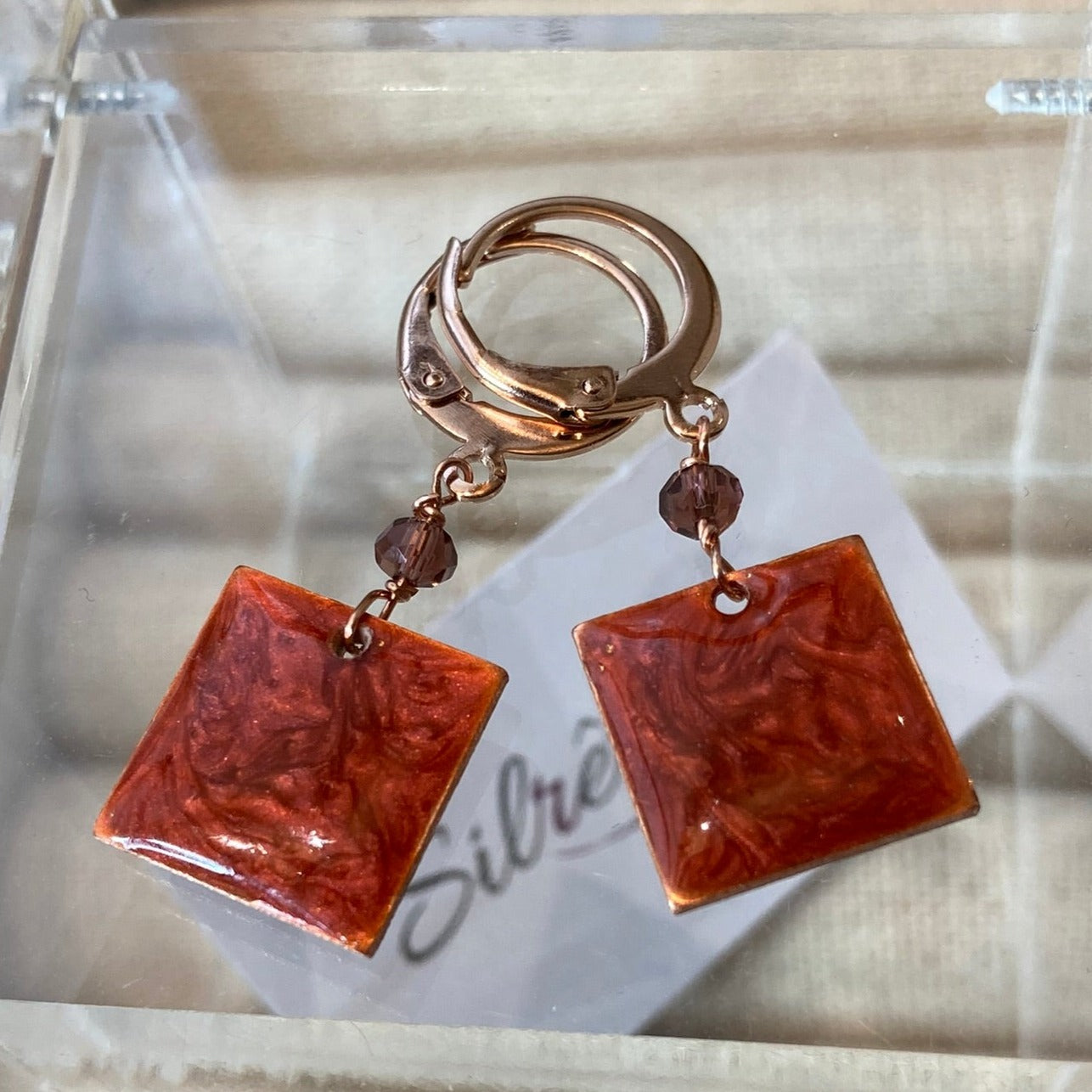 Copper pendant earrings embellished with small crystals.