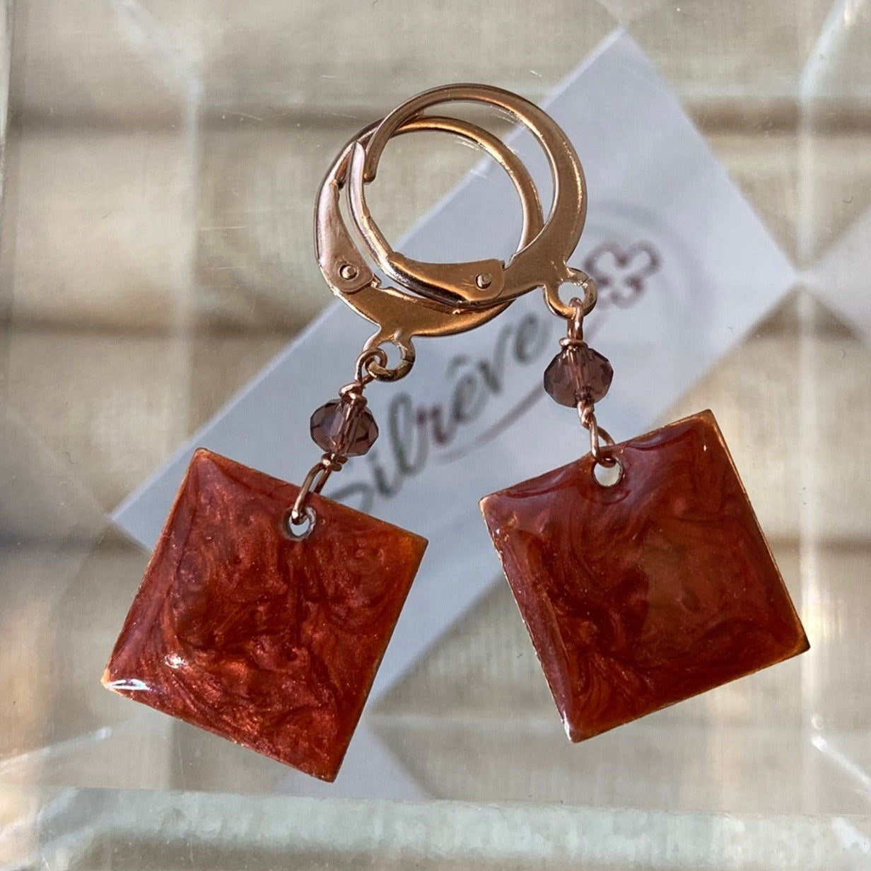 Copper pendant earrings embellished with small crystals.