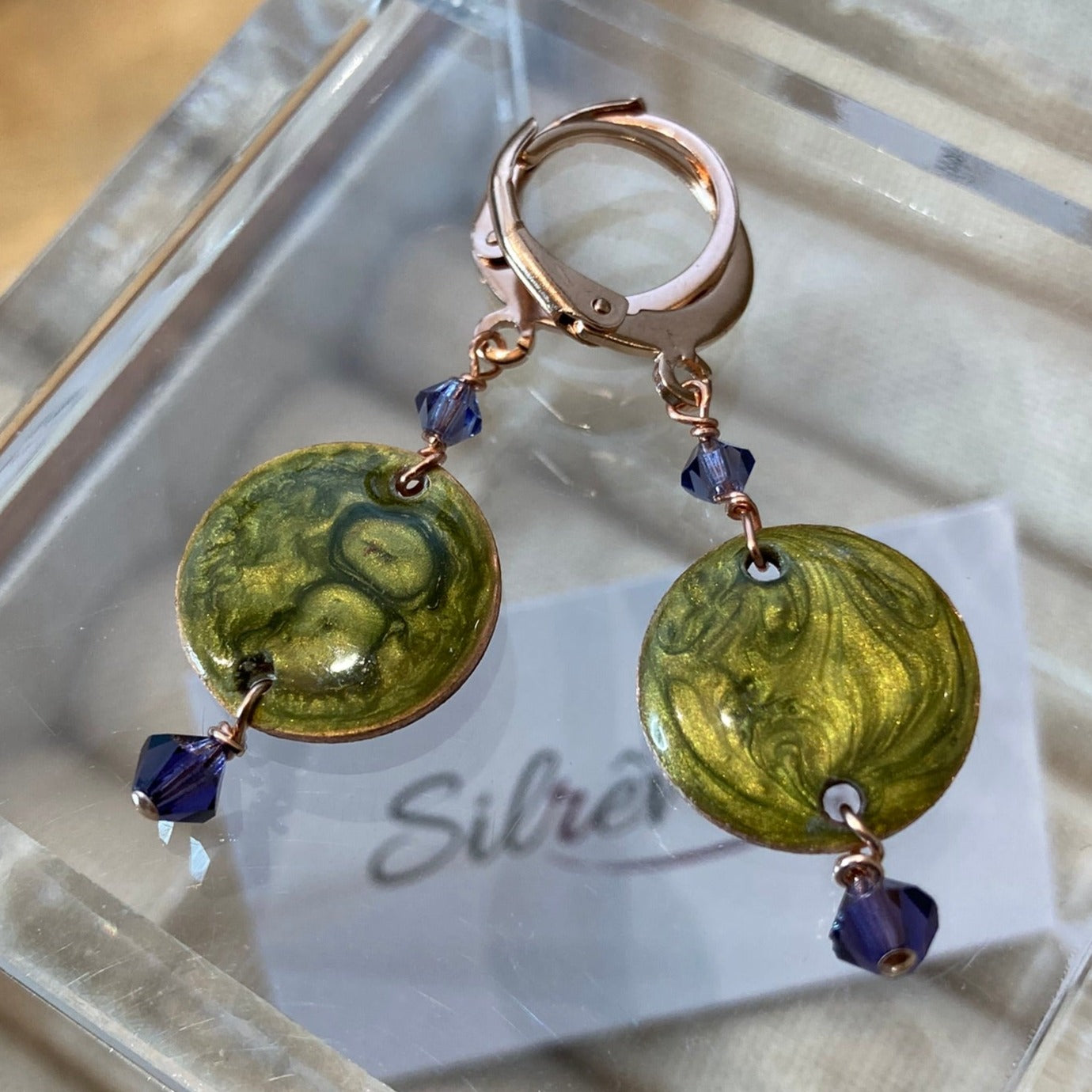 Copper pendant earrings embellished with small crystals.