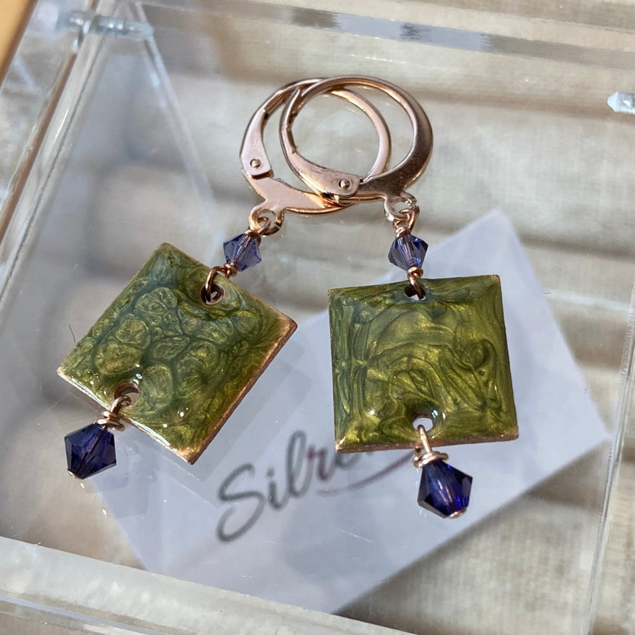 Copper pendant earrings embellished with small crystals.