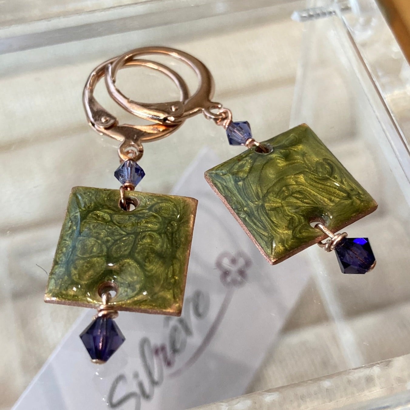 Copper pendant earrings embellished with small crystals.