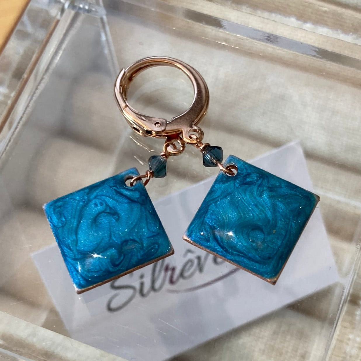 Copper pendant earrings embellished with small crystals.