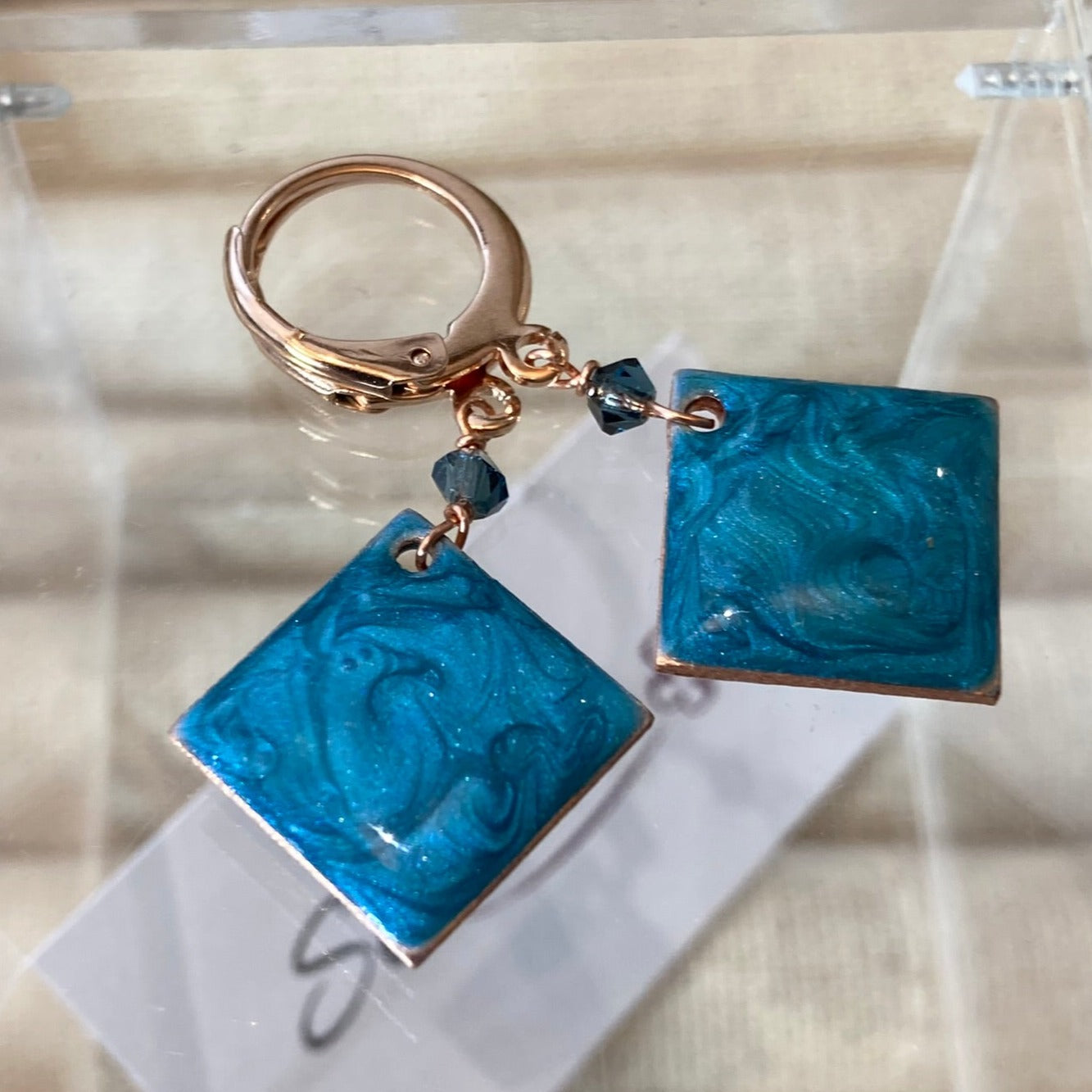 Copper pendant earrings embellished with small crystals.