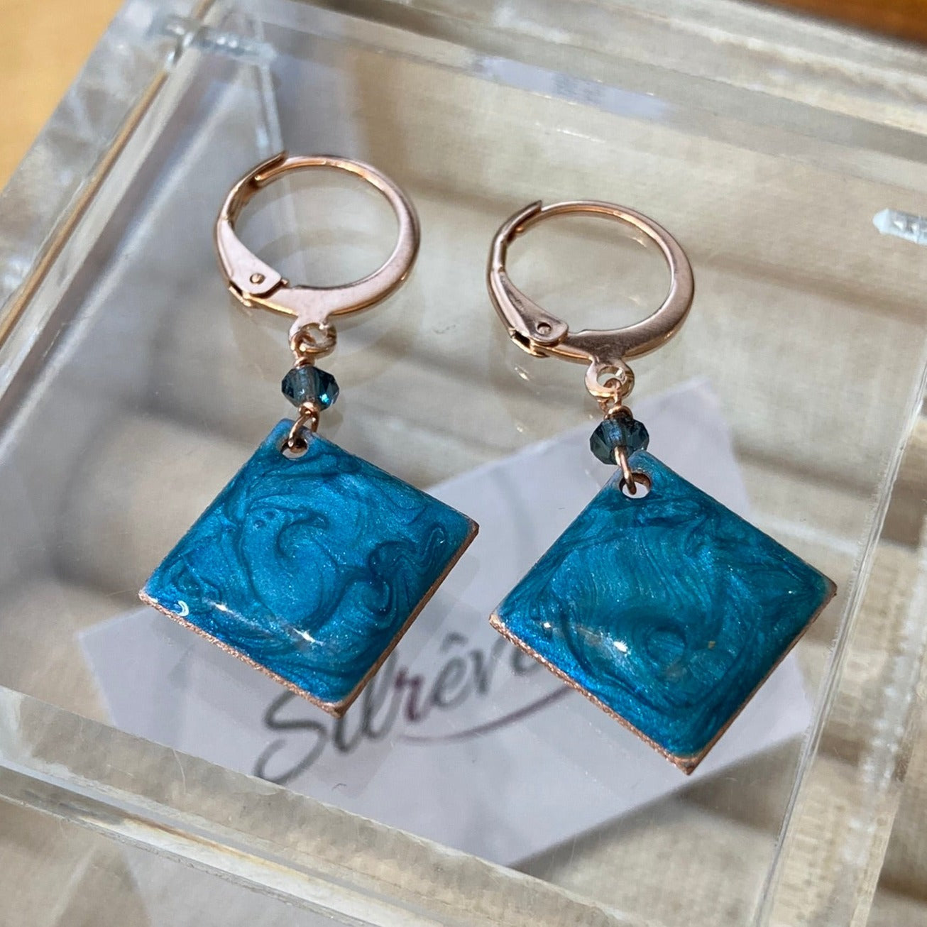 Copper pendant earrings embellished with small crystals.