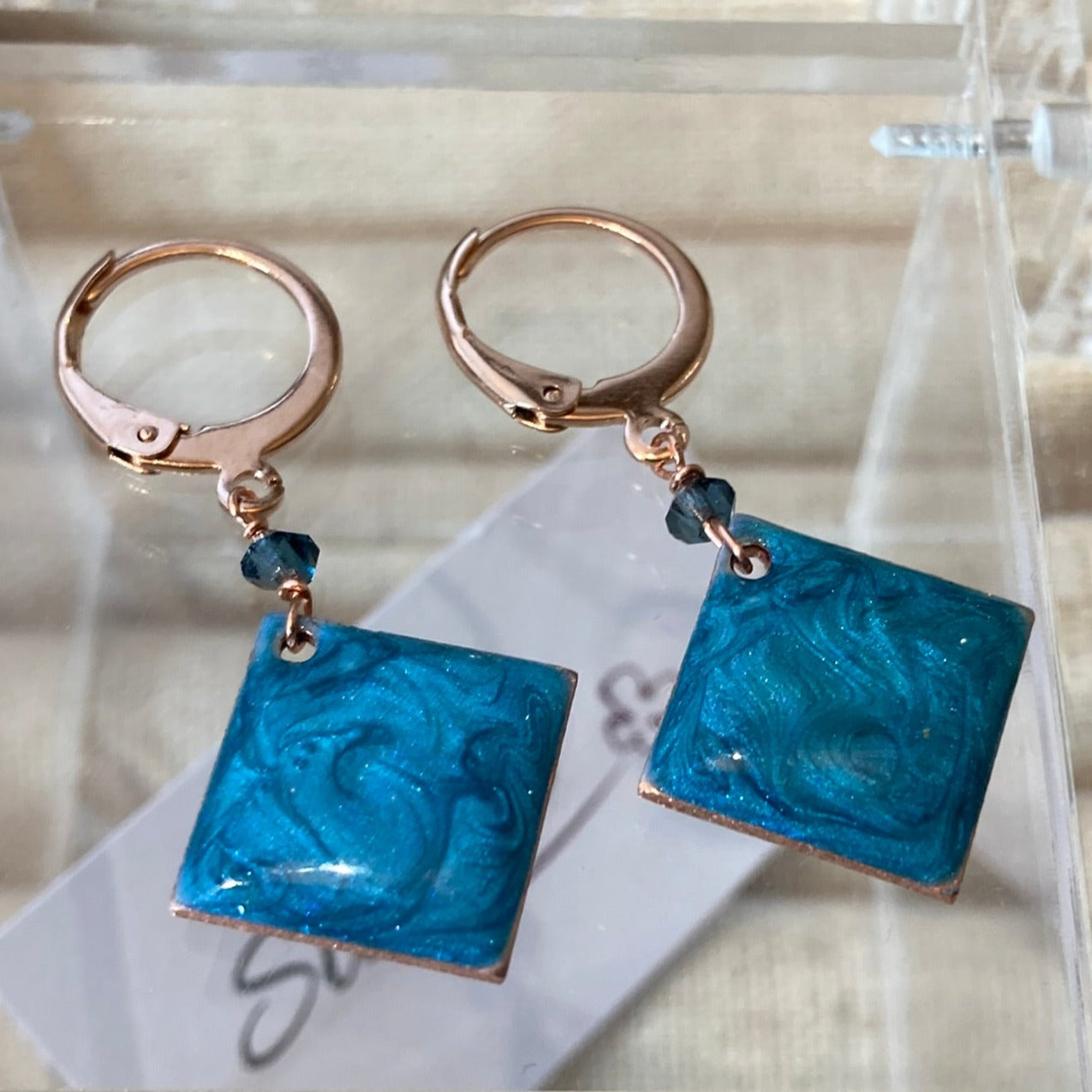 Copper pendant earrings embellished with small crystals.