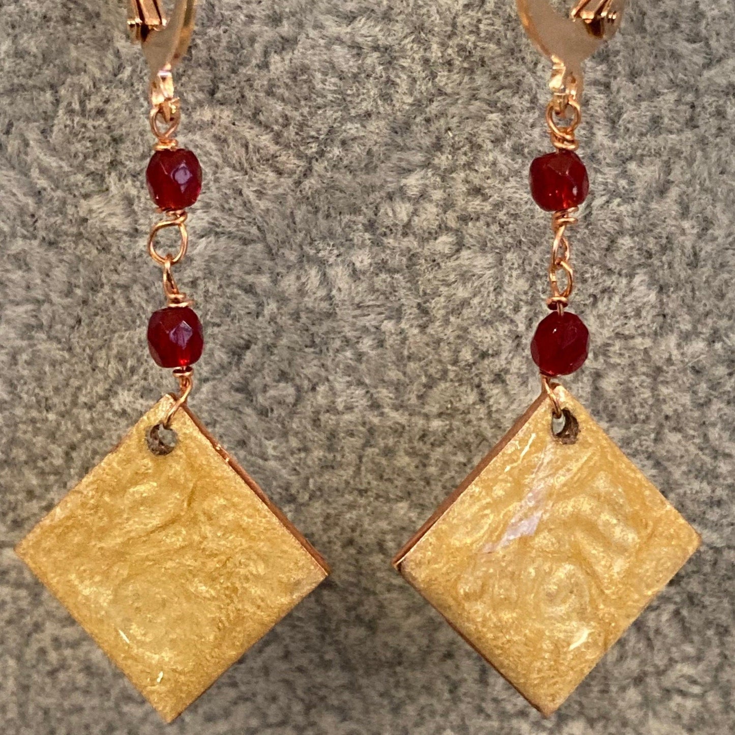 Copper pendant earrings embellished with small crystals.